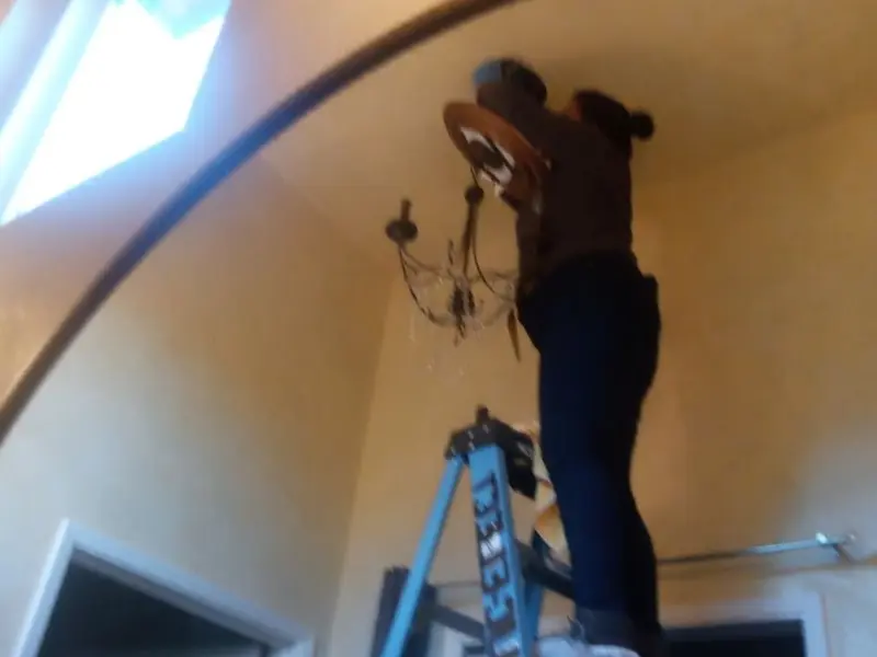 Electrician installing a chandelier in a Glenpool residence